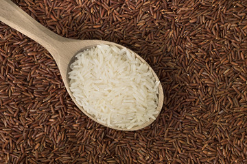 White rice in a wooden spoon on red rice background