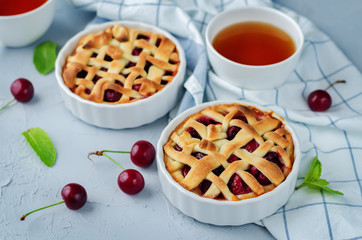 Cherry pies with fresh cherries oand cups of tea