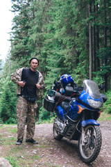 Motorcyclist man and Adventure Motorbike with beautiful mountains pine forest. Motorcycle trip. off road Traveling, Lifestyle Travel vacations sport outdoor concept vertical photo