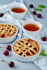 Cherry pies with fresh cherries oand cups of tea