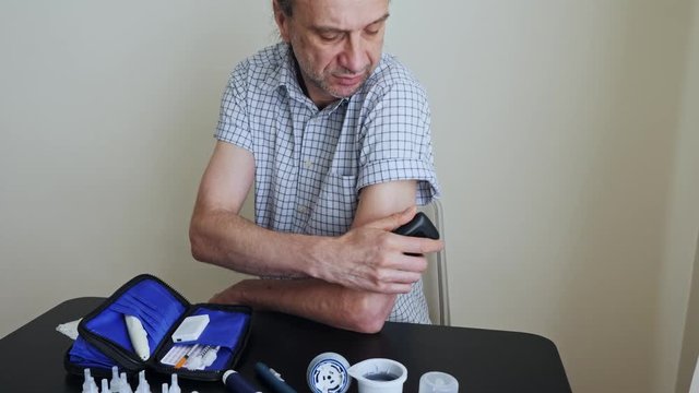 A man using a non-invasive glucose meter to measuring glucose level blood