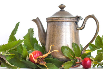 Retro pewter antique, silver color old fashioned teapot with a homegrown red wild rose rose-hips for healthy medicinal tea on a white background