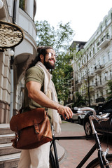 Obraz premium My vehicle. Delighted handsome man smiling while standing near his bike