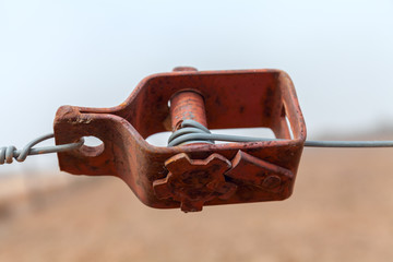 Old wire tensioner of a wire fence in a field closeup