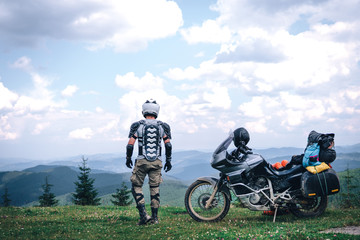 Motorcyclist man looking at the distance and Adventure Motorbike on the top of the mountain. Motorcycle trip. off road Traveling, Lifestyle Travel vacations sport outdoor concept.
