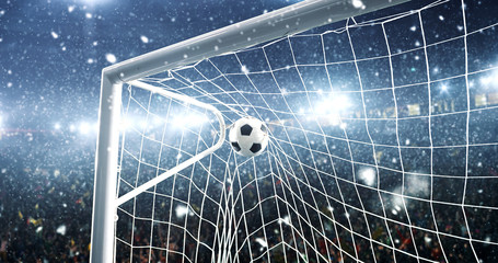 Photo of the ball that flies into a goal on a professional soccer stadium while it's snowing
