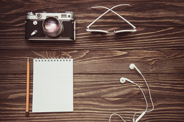 flatlay on wooden background retro camera, sunglasses, notepad and headphones