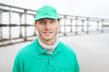 Adult volunteer man in green uniform standing and looking at camera