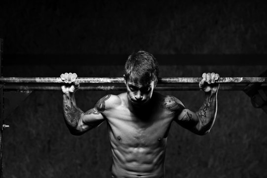 Muscular male athlete doing pull up exercise on horizontal bar. sports, fitness concept.