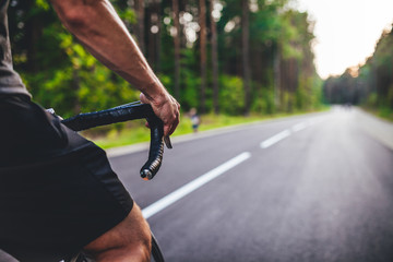 Road bike cyclist, man cycling on empty road in sunset