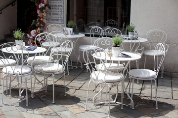 outdoor terrace of cafe with beautiful white wrought iron chairs and table in sunny summer day.