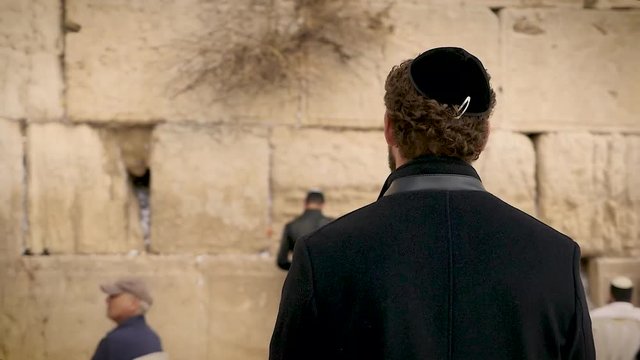 Man standing in front of the wailing wall in Jerusalem