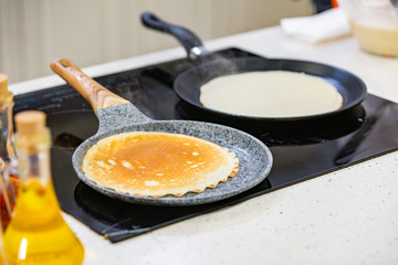 kitchen Preparation: the chef fries fresh pancakes in two pans