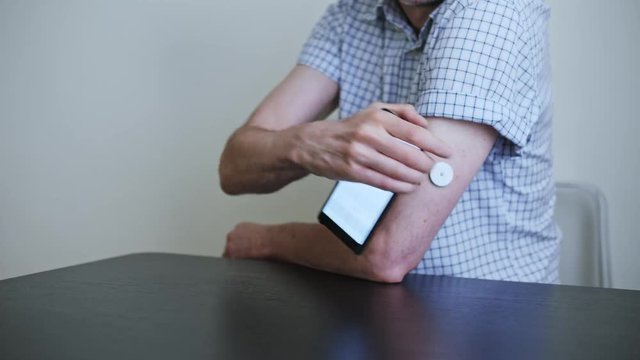 A man hands brings to the hand the smartphone for measuring glucose in the blood