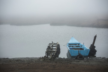 An old fishing boat standing still in river Evros, on a winter foggy morning