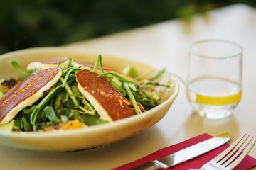 Salad with rucola, vegetables, oranges with fried cheese and greens.