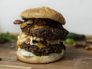Big double cheese burger with 500g of beef, vegetables, bacon, sauce and fries. Served on a wooden cutting board