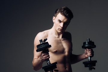 Work out concept. Macho on confident face with muscular figure, sportsman, bodybuilder. Man with torso, muscular macho with six packs, holds dumbbells, dark background. Guy attractive working out.