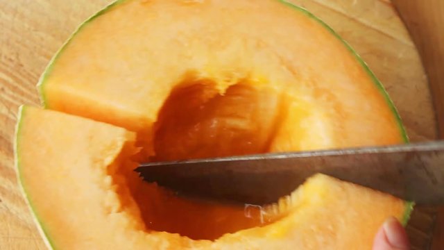 A woman cuts up a ripe melon