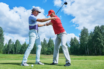 Golf training. Instructor trains new player in summer