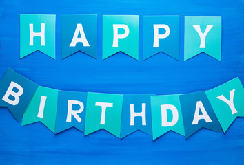 Happy birthday title with green and blue letters.  Paper decor on the blue background