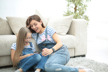 mother and her little daughter use a smartphone to view the photo