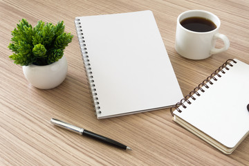 Notebook with coffee cup and potted plant on wood desk. Text copy space.