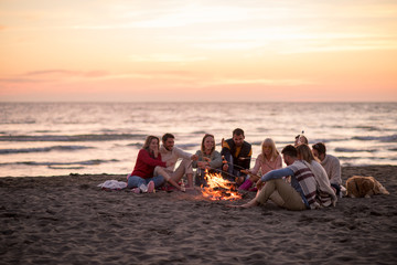 Group Of Young Friends Sitting By The Fire at beach - Powered by Adobe