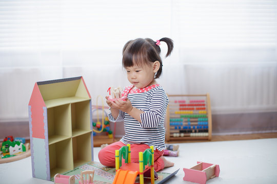 Baby Girl Playing Doll House At Home