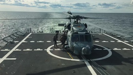 Special forces getting onboard navy helicopter at sea.