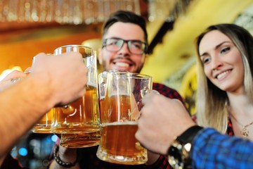 Laughing friends communicate and drink beer in a cafe or a pub