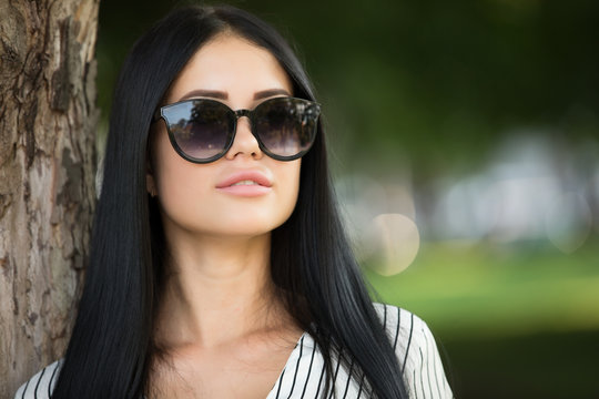 Young woman in sunglasses closeup portrait, hair after botox keratin treatment