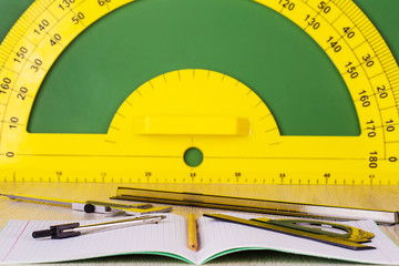 Business concept: pencil, compass, notebook, ruler, caliper and green chalkboard with protractor