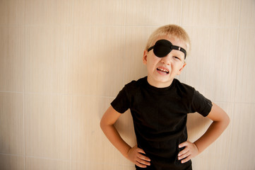 Happy blond child with black medical patch occluder on eye