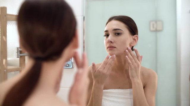 Skin Care. Woman Touching Face And Looking At Mirror At Bathroom
