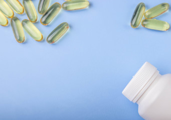 transparent capsules of fish oil and a white bottle on a blue background