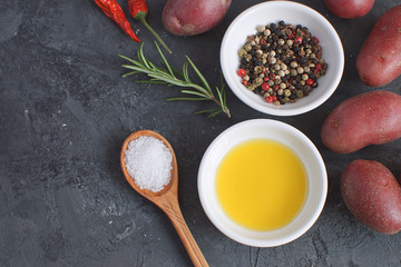 Olive oil porcelain plate Rosemary branch Pepper mix Chili pepper Seasoning Spices Raw potato Cooking concept Black concrete background Top view Copy space Flat lay