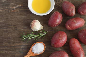 Olive oil porcelain plate Rosemary branch Pepper mix Garlic Seasoning Spices Raw potato Cooking concept Wooden background Top view Copy space Flat lay