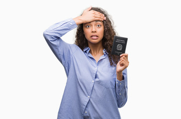 Young hispanic woman holding passport of Italy stressed with hand on head, shocked with shame and...