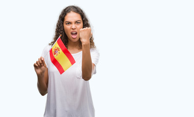 Young hispanic woman holding flag of Spain annoyed and frustrated shouting with anger, crazy and yelling with raised hand, anger concept