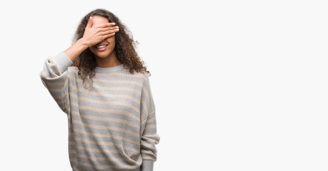 Beautiful young hispanic woman wearing stripes sweater smiling and laughing with hand on face covering eyes for surprise. Blind concept.