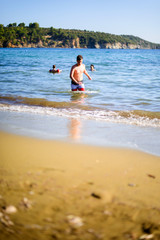 Young boy in swimsuit walking through the sea