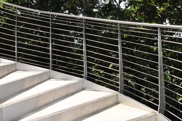 Spiral steps with stainless steel railings against a lush background of greenery