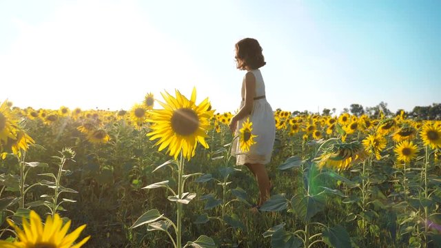 Happy little girl running happy free across the field with sunflowers. slow motion video . smelling big sunflower on summer field. Delight of a pleasant smell. Summer holiday. concept happiness girl