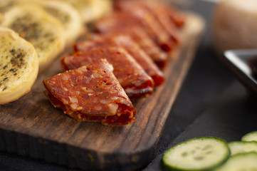 Sliced ​​sausage salami chorizo ​​on cutting board, with cheese and toasted bread slices