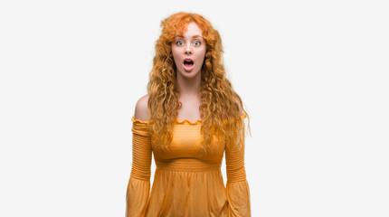 Young redhead woman afraid and shocked with surprise expression, fear and excited face.