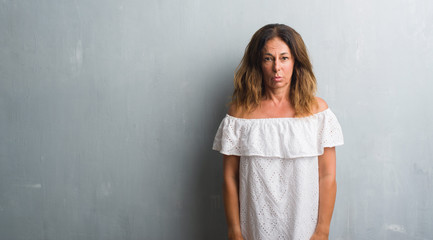 Fototapeta premium Middle age hispanic woman standing over grey grunge wall depressed and worry for distress, crying angry and afraid. Sad expression.