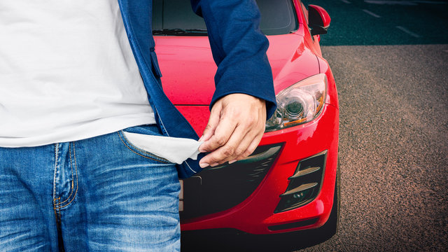 Man showing his empty pockets with red car background.