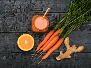 Mug with carrot smoothie, ginger root and orange on wooden table. The view from the top. Flat lay.