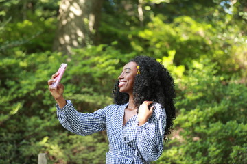 Young stylish black woman taking selfie